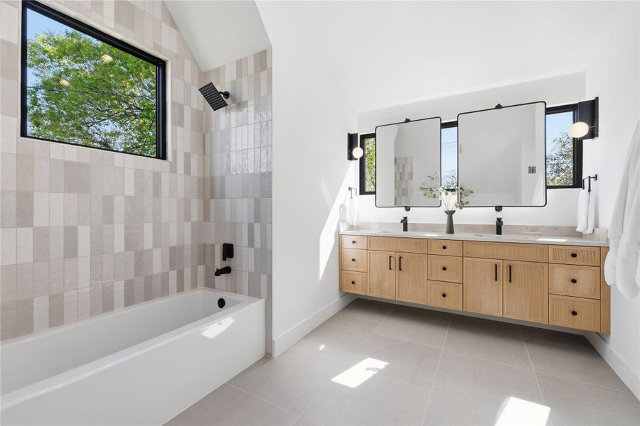 A chic bathroom offers a clean-lined bathtub, a dual vanity with ample storage, and luminous tile flooring. A chic bathroom offers a clean-lined bathtub, a dual vanity with ample storage, and luminous tile flooring.