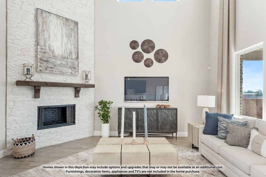Living room with two-story white stone fireplace, wall-mounted TV, and neutral sofa with blue accent pillows Living room with two-story white stone fireplace, wall-mounted TV, and neutral sofa with blue accent pillows