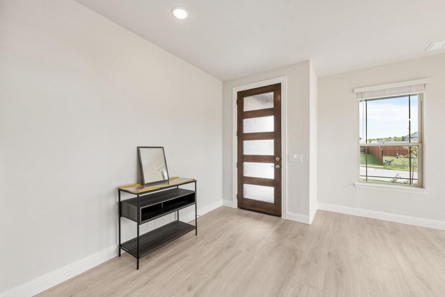 Entryway with light wood floors, dark wood glass-panel door, and black metal console table with mirror.