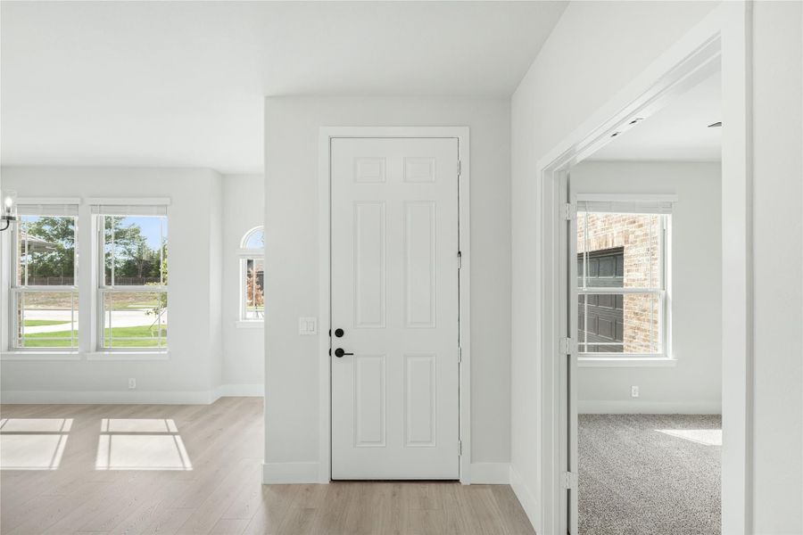 Bright entryway with white six-panel door, light wood floors, and large windows