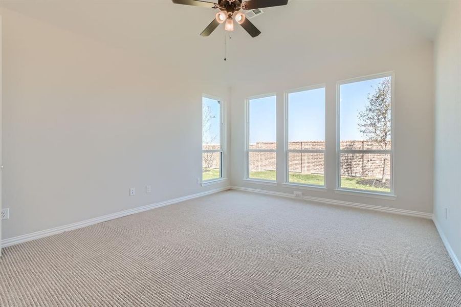 Carpeted empty room featuring a high ceiling and ceiling fan