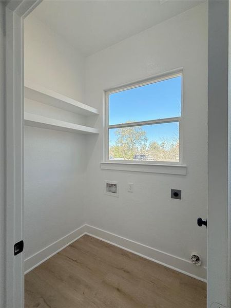 Spacious laundry room with built-in shelving for easy organizationand a large window providing a view of the outdoors, making chores feel less like a task.