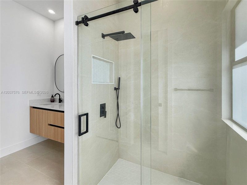 Contemporary shower enclosure with clear glass paneling and a matte black barn-style hardware system