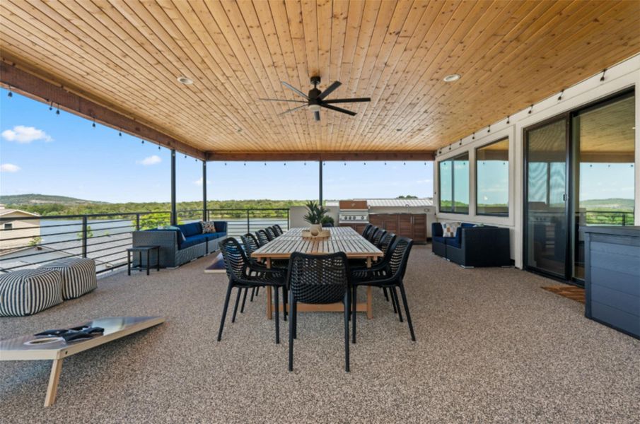 This spacious outdoor patio features a wooden ceiling with a fan and offers stunning views of the surrounding landscape. Perfect for entertaining and relaxation.