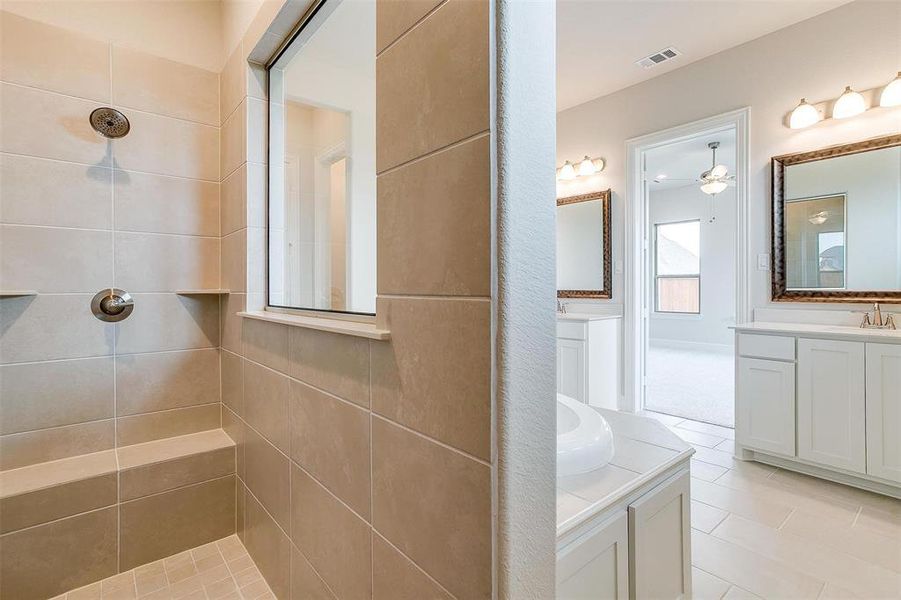 Bathroom featuring dual vanity, ceiling fan, tile patterned flooring, and a tile shower