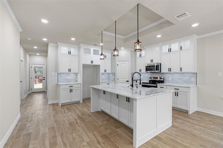 Kitchen featuring white cabinetry, stainless steel appliances, and a kitchen island with sink