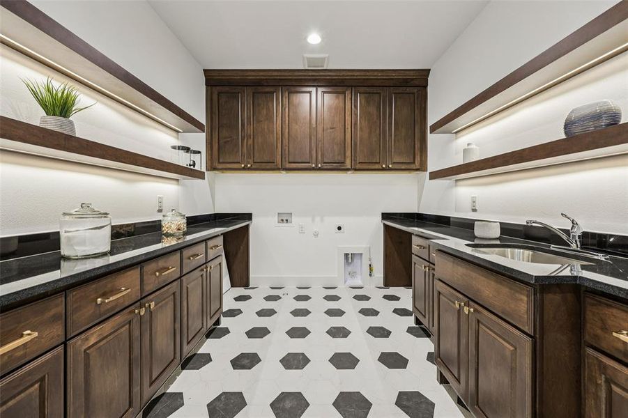 Dedicated utility room with dark wood cabinetry, black countertops, and a stainless steel sink