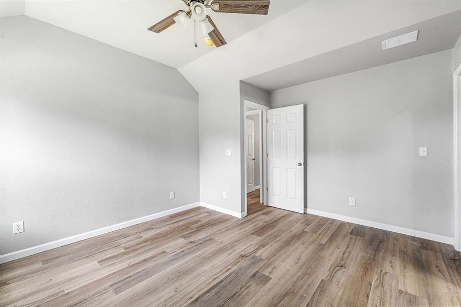 Unfurnished bedroom featuring vaulted ceiling, wood finished floors, baseboards, and a ceiling fan Unfurnished bedroom featuring vaulted ceiling, wood finished floors, baseboards, and a ceiling fan