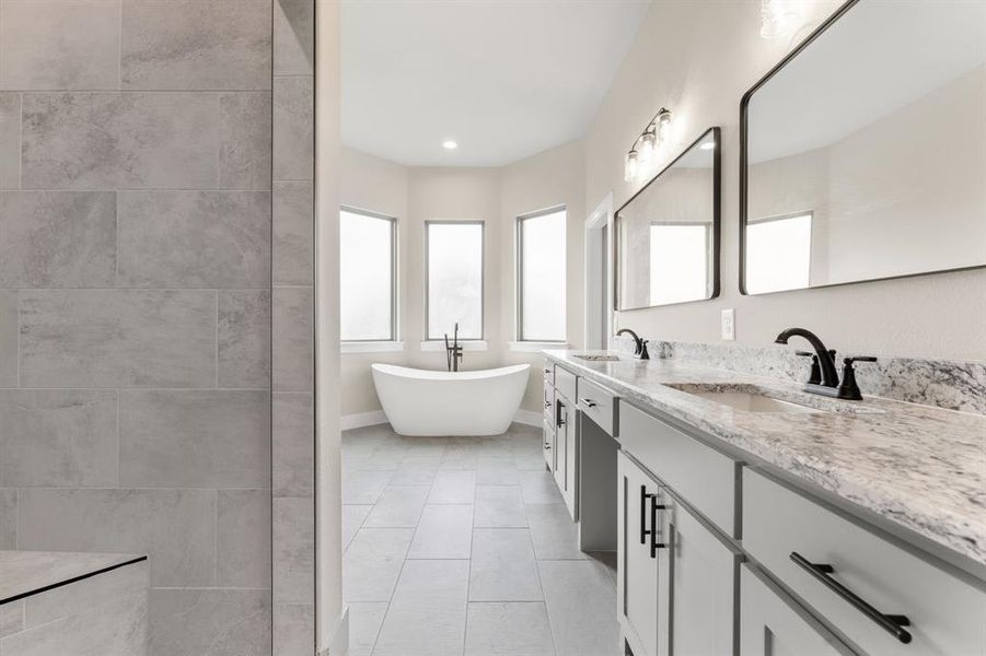 Bathroom featuring a tub to relax in, vanity, and tile patterned flooring