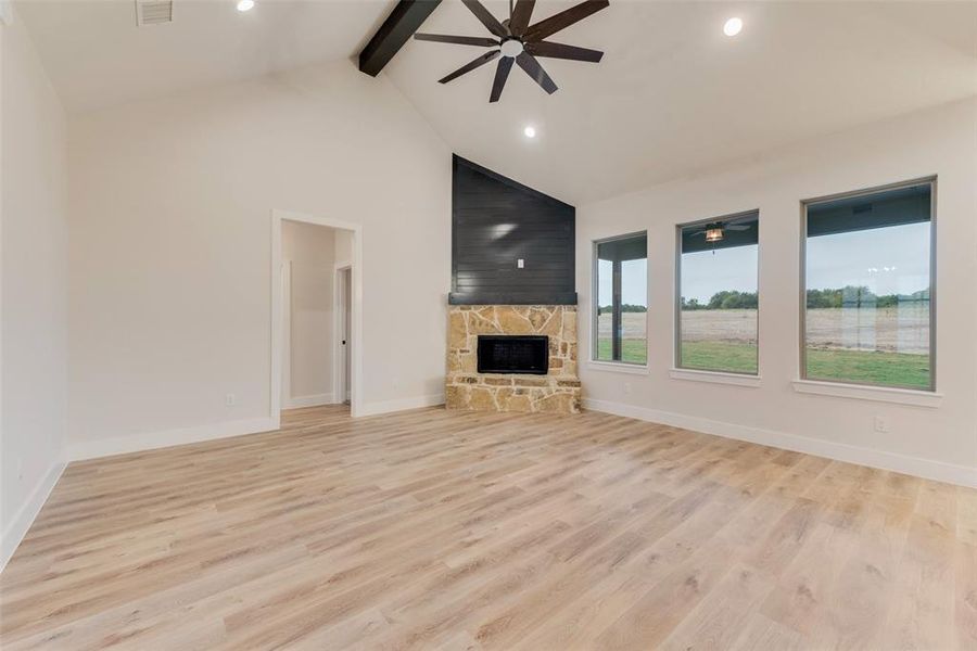 Unfurnished living room with a ceiling fan, light wood-style flooring, beamed ceiling, recessed lighting, and a fireplace Unfurnished living room with a ceiling fan, light wood-style flooring, beamed ceiling, recessed lighting, and a fireplace