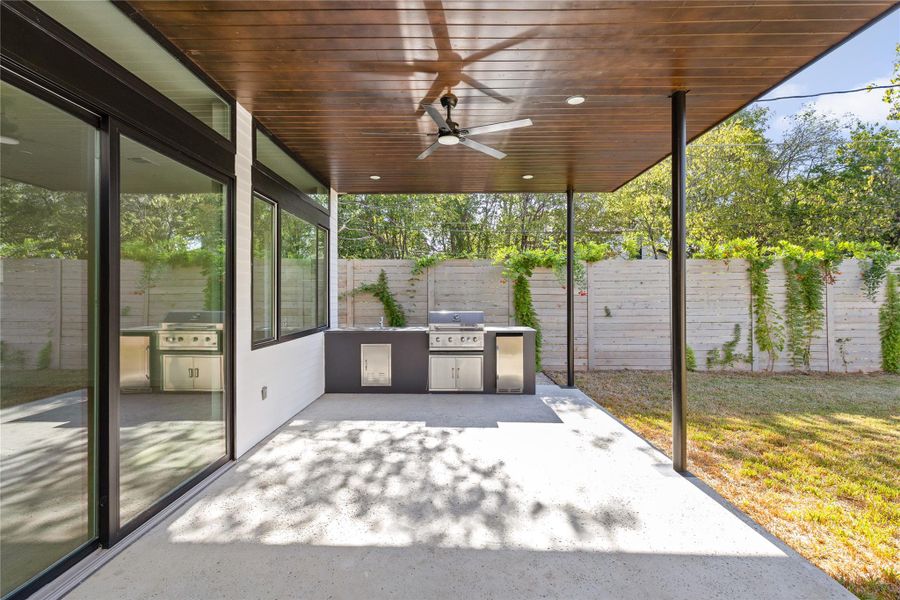 Fenced backyard featuring exterior kitchen, a patio, and ceiling fan