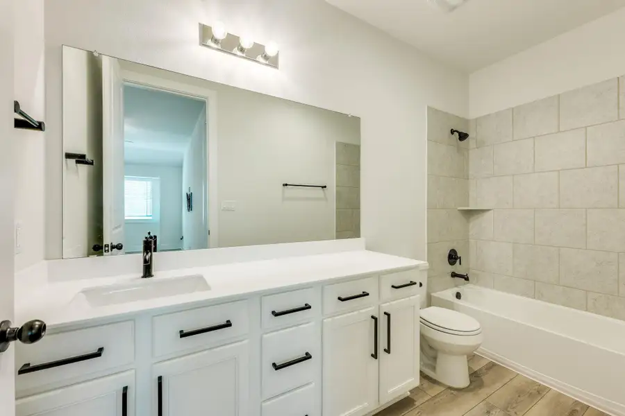 Bathroom featuring vanity, bathtub / shower combination, and light wood-style floors