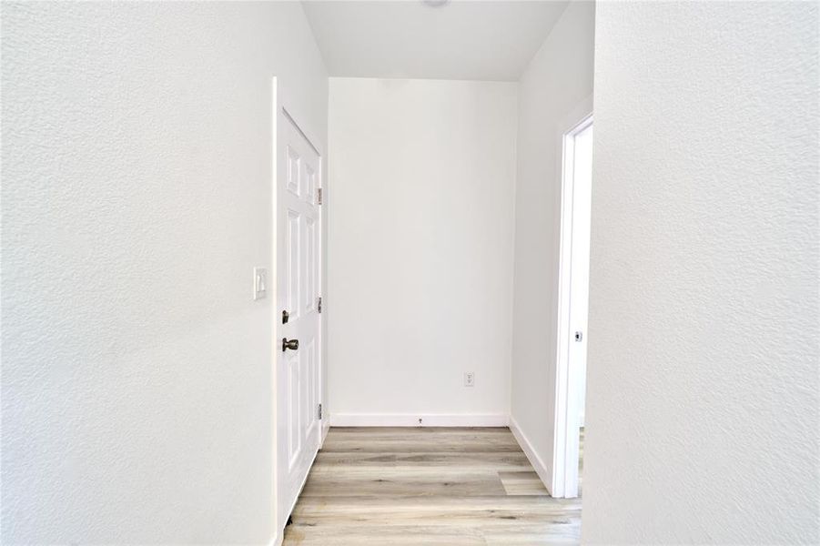 Entryway featuring wood-finish flooring, crisp white walls, and a recessed ceiling light