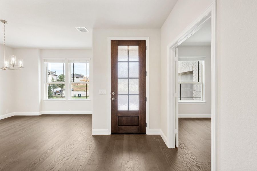 Entryway with dark wood front door with glass panels, hardwood floors, and pendant chandelier