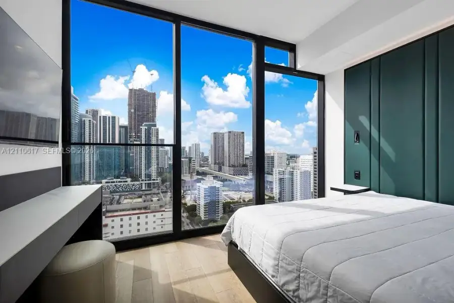 Floor-to-ceiling windows, custom green-paneled feature wall, wood-finish flooring, and built-in minimalist vanity Floor-to-ceiling windows, custom green-paneled feature wall, wood-finish flooring, and built-in minimalist vanity
