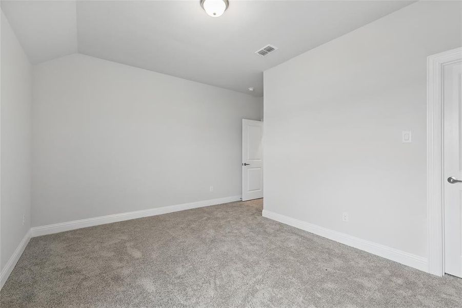 Carpeted spare room featuring lofted ceiling and baseboards Carpeted spare room featuring lofted ceiling and baseboards