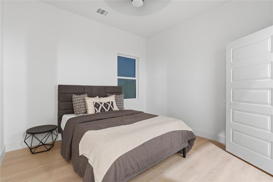 Bedroom featuring light wood-finish flooring, a contemporary window, and a paneled door