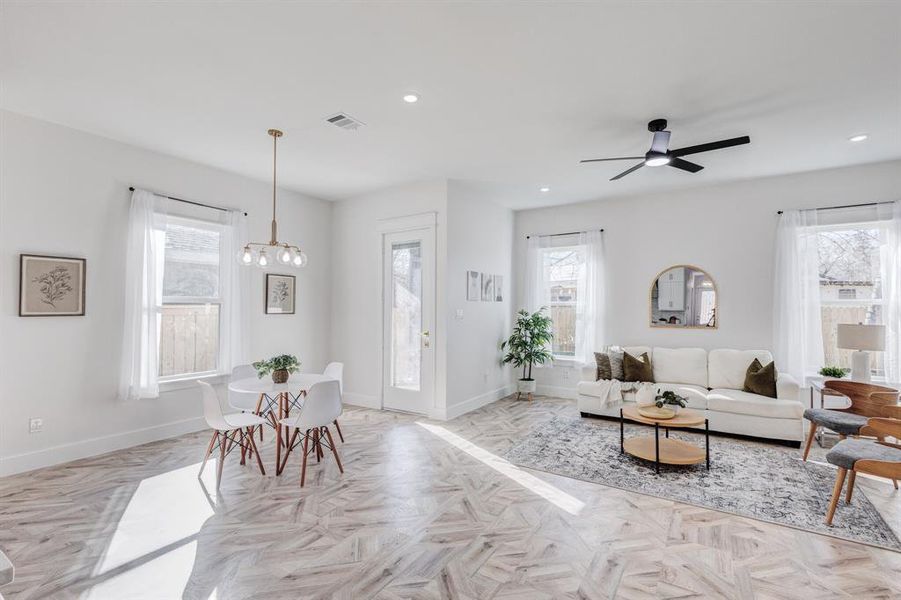 Living room featuring light parquet flooring, ceiling fan, and a healthy amount of sunlight