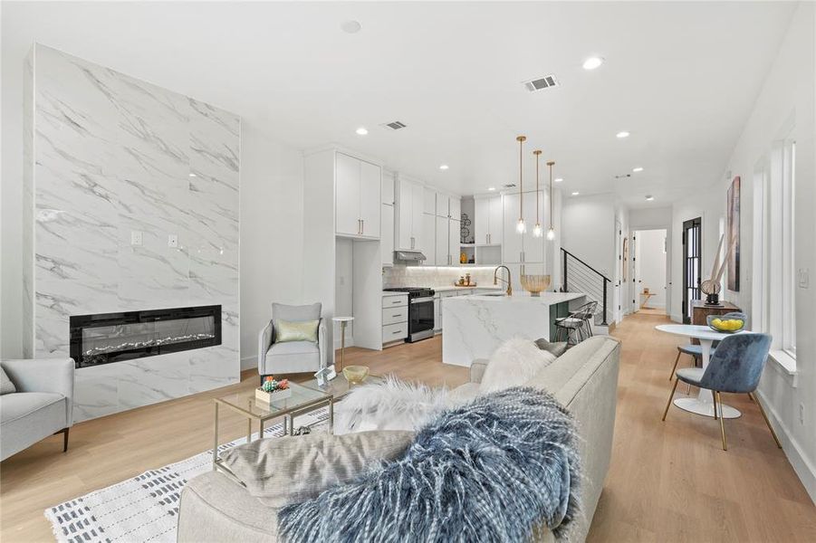 Living room featuring a high end fireplace, visible vents, and light wood finished floors