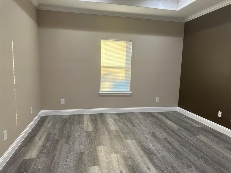 Empty room featuring ornamental molding, dark wood-style flooring, and baseboards