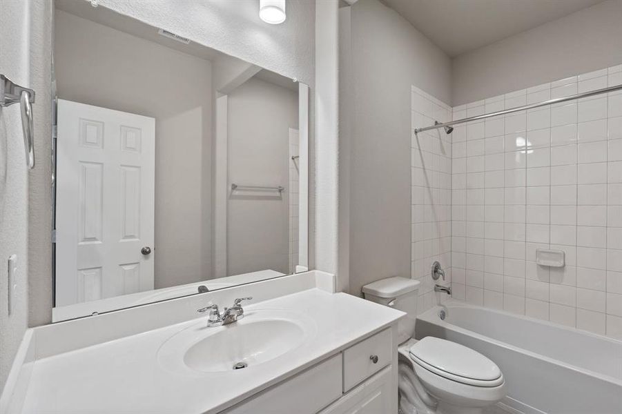 The secondary bath features tile flooring, white cabinetry and light countertops and a shower/tub combo. Perfect for accommodating any visiting family and friends.