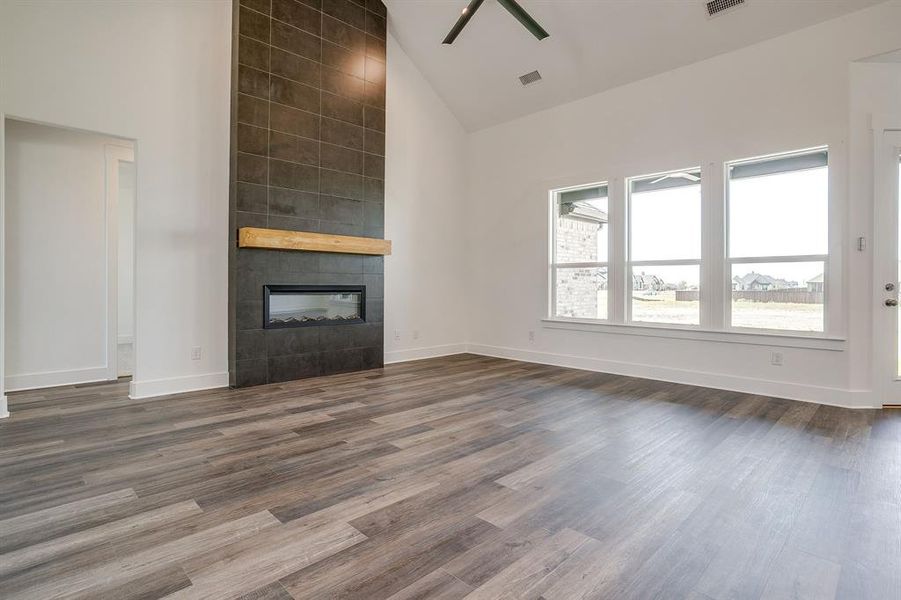 Unfurnished living room featuring lofted ceiling, a fireplace, ceiling fan, and dark wood-type flooring Unfurnished living room featuring lofted ceiling, a fireplace, ceiling fan, and dark wood-type flooring