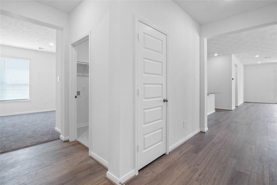 Flowing entry hallway featuring durable viny plank flooring, providing access to essential areas like the laundry room before opening up to the versatile Den.