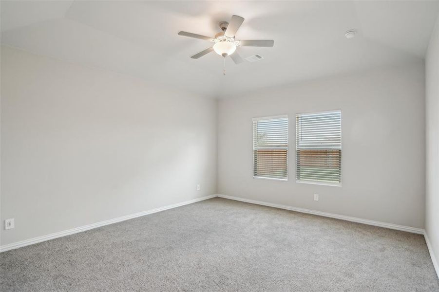 Empty room with carpet floors, ceiling fan, and vaulted ceiling