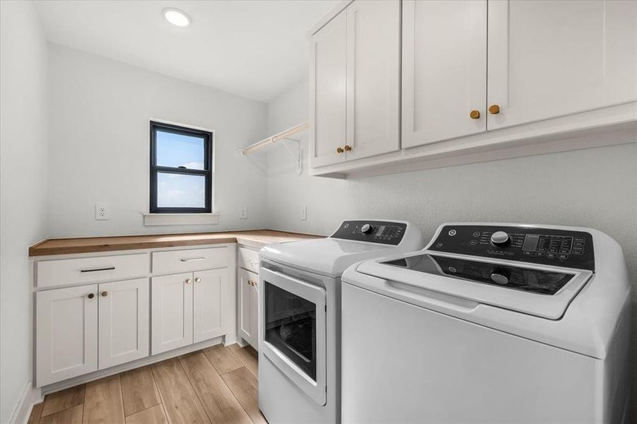 Large laundry room overlooks front of home.  Features butcher block countertops, drip dry hanging rod, and a ton of cabinet space for additional storage.  Electric W/D hookup for full size appliances.