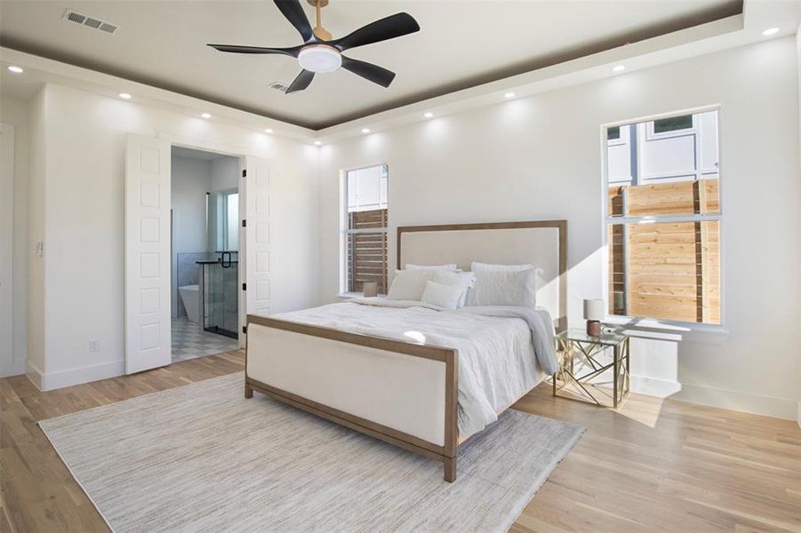 Bedroom featuring light wood-type flooring, ceiling fan, and connected bathroom