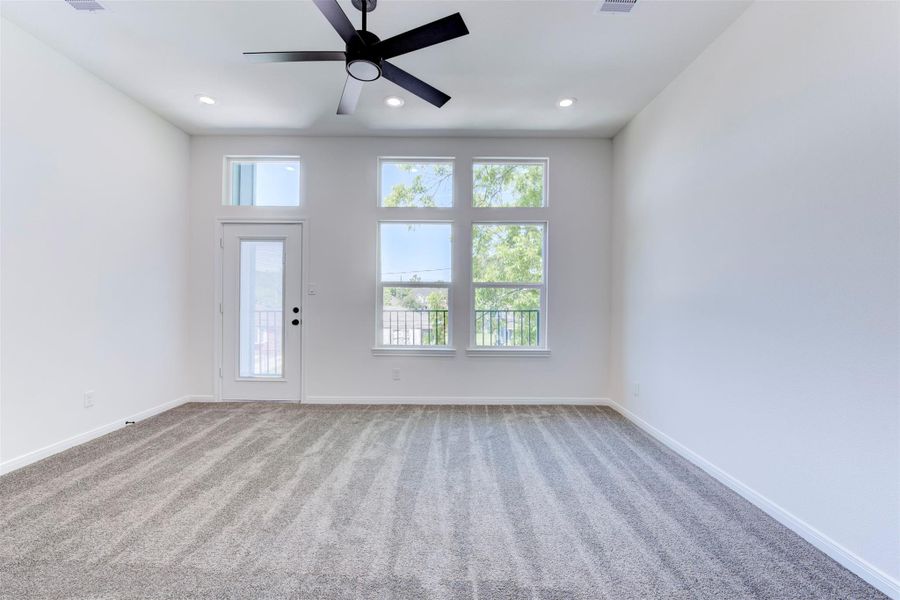 Light-filled primary bedroom featuring a ceiling fan with integrated light, recessed lighting, and soft carpet underfoot. Enjoy direct access to a private balcony for added indoor-outdoor living.