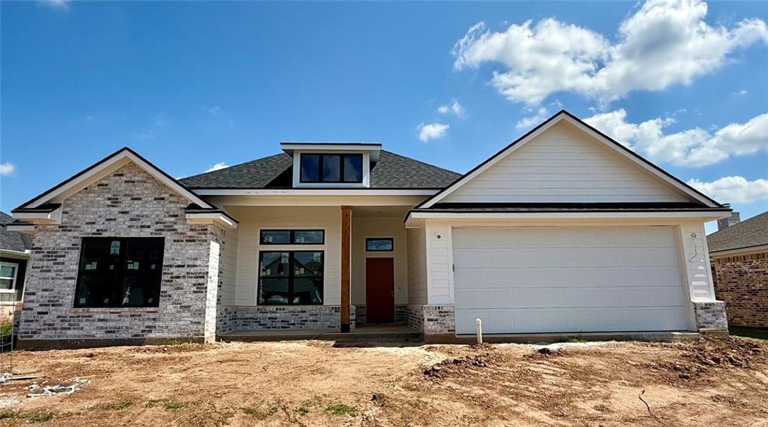 View of front of house with covered porch, brick siding, roof with shingles, and a garage View of front of house with covered porch, brick siding, roof with shingles, and a garage