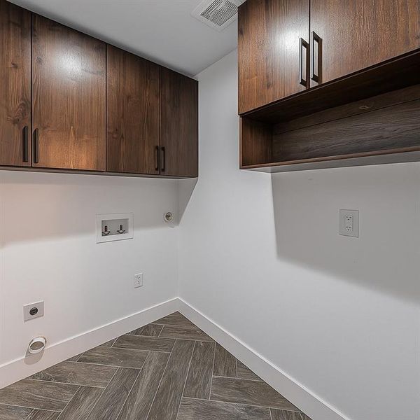 Laundry area featuring hookup for an electric dryer, cabinet space, and washer hookup Laundry area featuring hookup for an electric dryer, cabinet space, and washer hookup