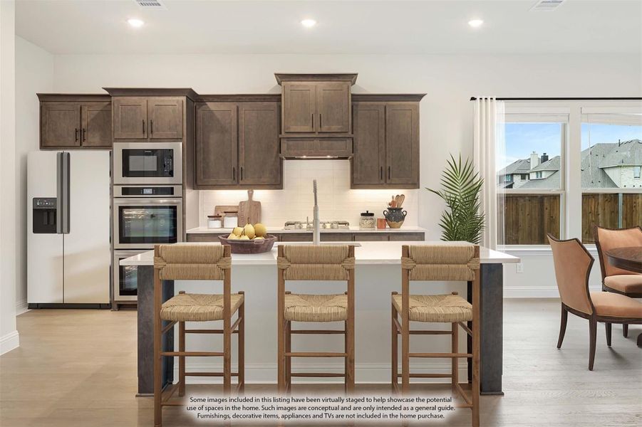 Kitchen with dark wood cabinets, center island with three bar stools, and stainless steel appliances Kitchen with dark wood cabinets, center island with three bar stools, and stainless steel appliances
