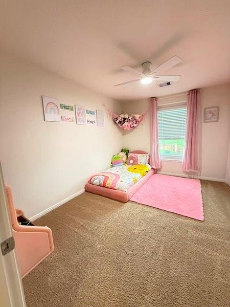 Spacious secondary bedroom with plush carpet, ceiling fan, and natural light Spacious secondary bedroom with plush carpet, ceiling fan, and natural light