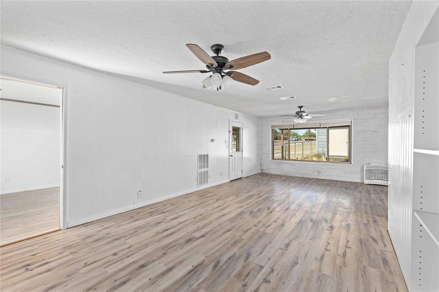 Unfurnished primary bedroom featuring light wood finished floors, a textured ceiling, and ceiling fan
