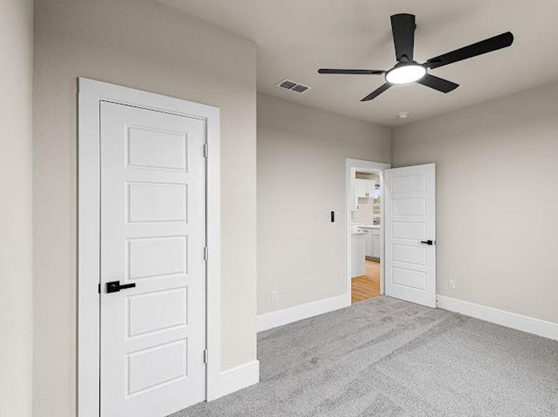 Unfurnished bedroom featuring light colored carpet and a ceiling fan Unfurnished bedroom featuring light colored carpet and a ceiling fan