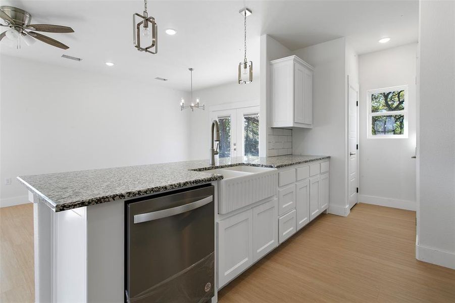 Kitchen with white cabinets, sink, hanging light fixtures, stainless steel dishwasher, and ceiling fan