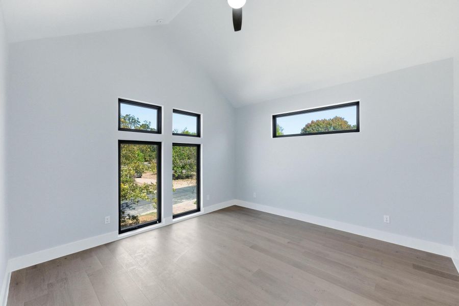 Spare room featuring light wood-style floors, high vaulted ceiling, and ceiling fan Spare room featuring light wood-style floors, high vaulted ceiling, and ceiling fan