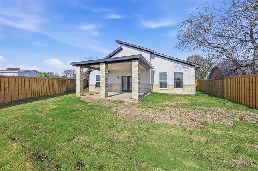 Back of house with a patio area, a fenced backyard, and stone siding Back of house with a patio area, a fenced backyard, and stone siding