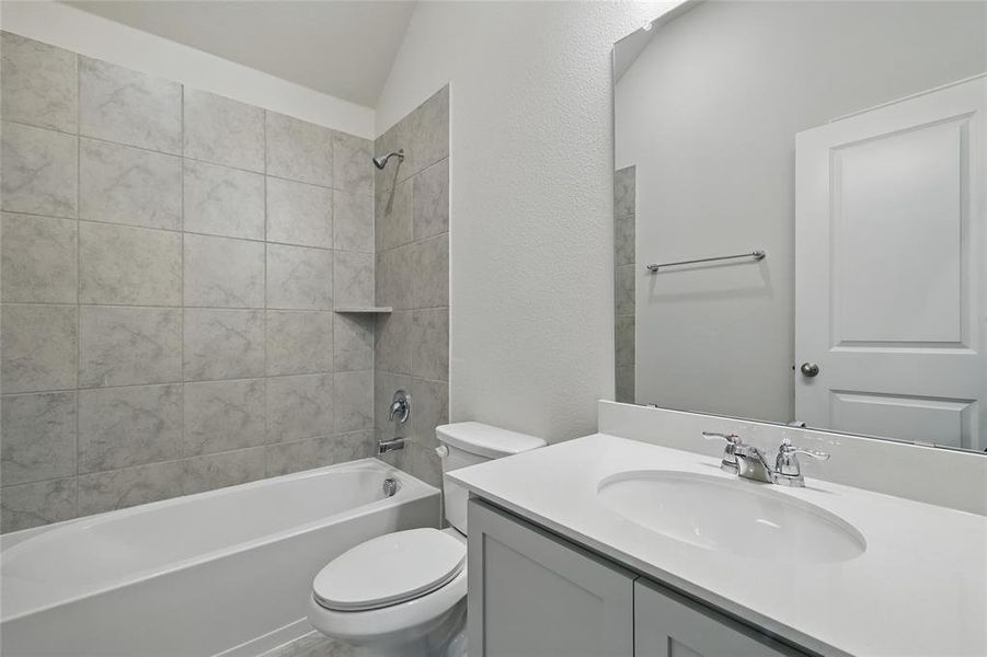 Full bathroom with vanity, shower / washtub combination, a textured wall, and lofted ceiling Full bathroom with vanity, shower / washtub combination, a textured wall, and lofted ceiling