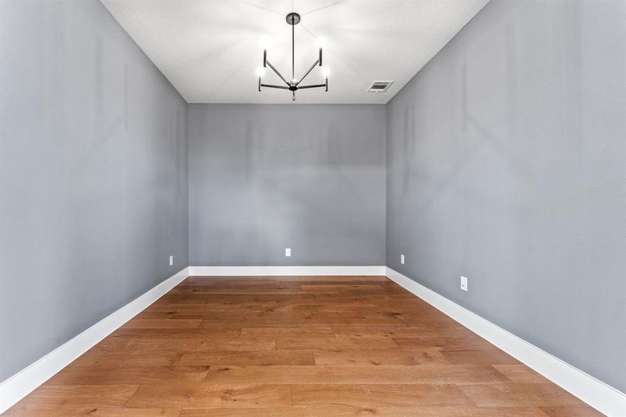 Unfurnished dining area with hardwood / wood-style floors and a notable chandelier