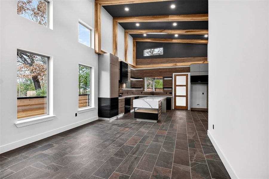 Unfurnished living room with vaulted ceiling, recessed lighting, and dark stone finish floors