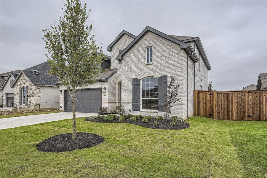 French country home featuring brick siding, a garage, concrete driveway, and roof with shingles
