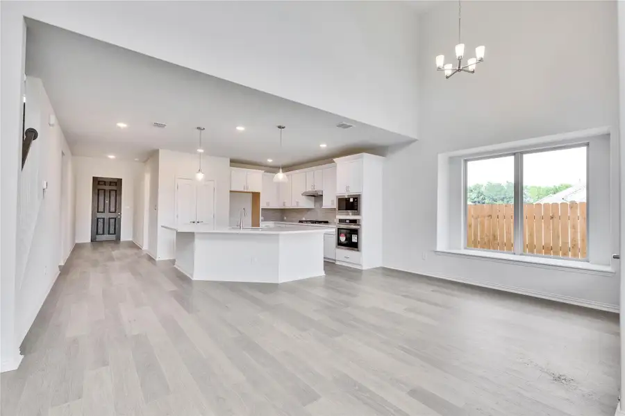 Unfurnished living room featuring light wood finished floors, a chandelier, baseboards, recessed lighting, and a sink Unfurnished living room featuring light wood finished floors, a chandelier, baseboards, recessed lighting, and a sink