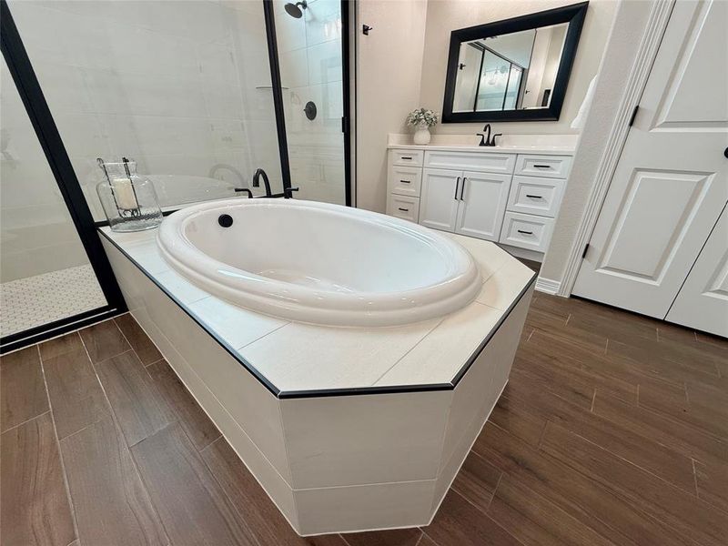 Full bathroom featuring a shower stall, a garden tub, vanity, and wood tiled floors Full bathroom featuring a shower stall, a garden tub, vanity, and wood tiled floors
