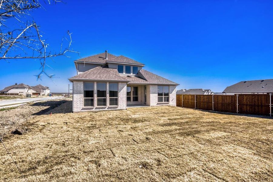Rear view of property featuring a patio, brick siding, a fenced backyard, and roof with shingles