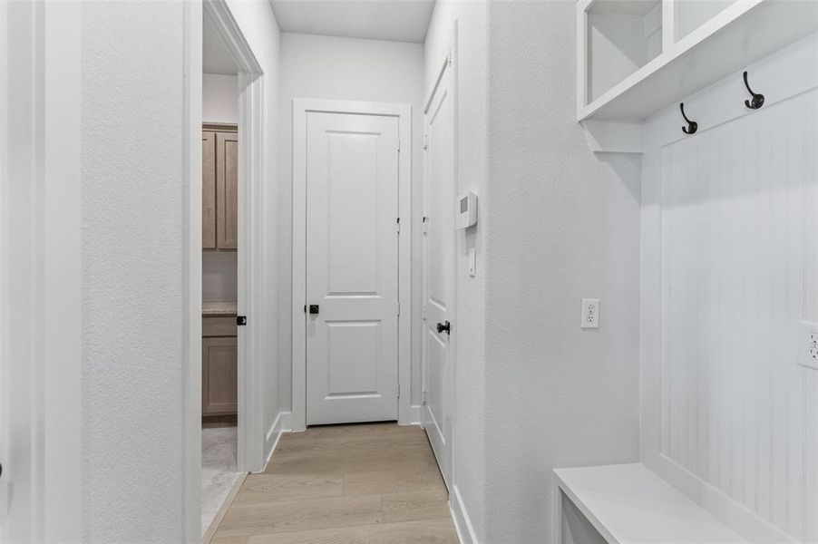 Mudroom featuring light wood finished floors and a textured wall Mudroom featuring light wood finished floors and a textured wall