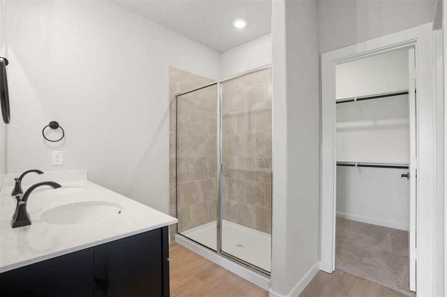 Full bath with a stall shower, light wood finished floors, a walk in closet, and recessed lighting Full bath with a stall shower, light wood finished floors, a walk in closet, and recessed lighting