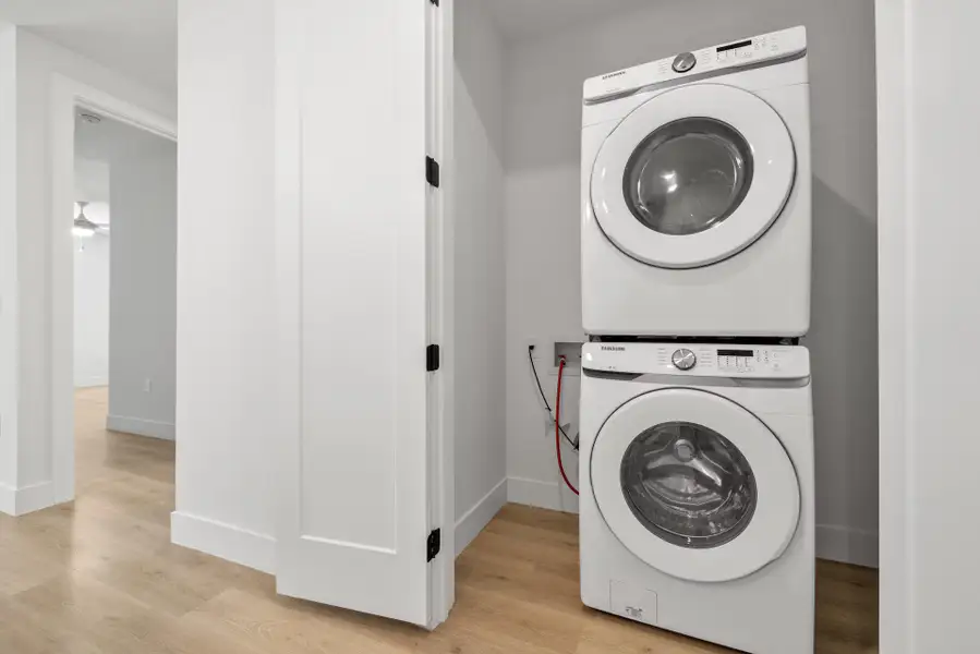 Laundry room featuring stacked washing machine and dryer and light wood-type flooring